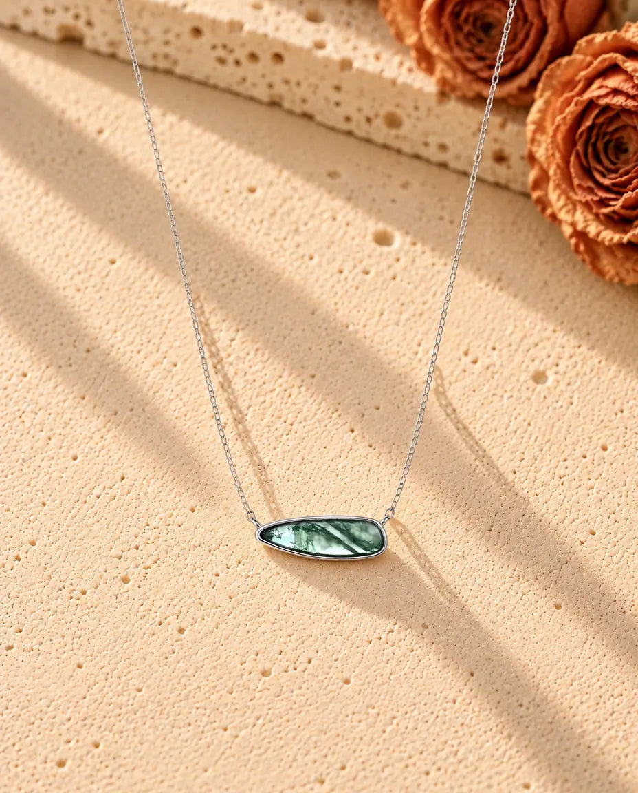 Collana Barretta Agata Muschiata in Argento 925 - la collana intera distesa a lunga V su una superficie chiara ruvida