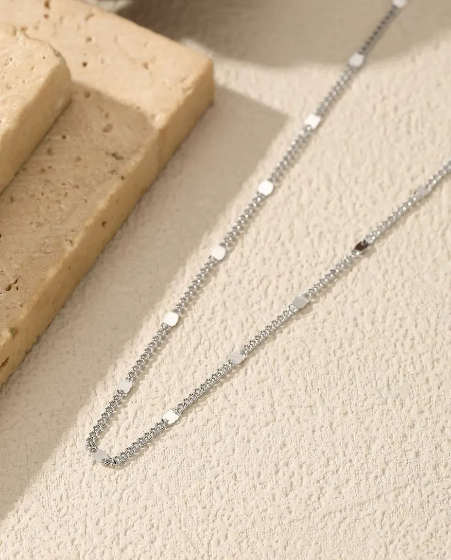 Collana Catena a Stazioni in Argento 925 - adagiata su una superficie chiara accanto a una lastra di travertino