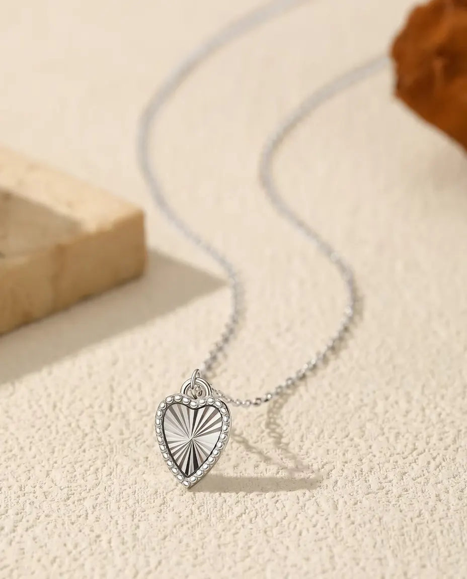 Collana con Ciondolo a Cuore in Argento 925 - ciondolo su una superficie chiara accanto a una lastra di travertino
