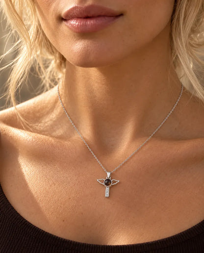 Donna con maglia marrone che indossa la collana argentata con croce e ali d'angelo