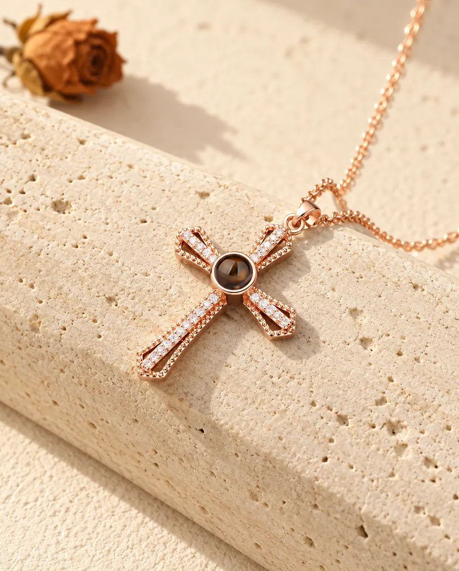 Collana con croce a pavé color oro rosa e pietra di proiezione appoggiata contro il travertino