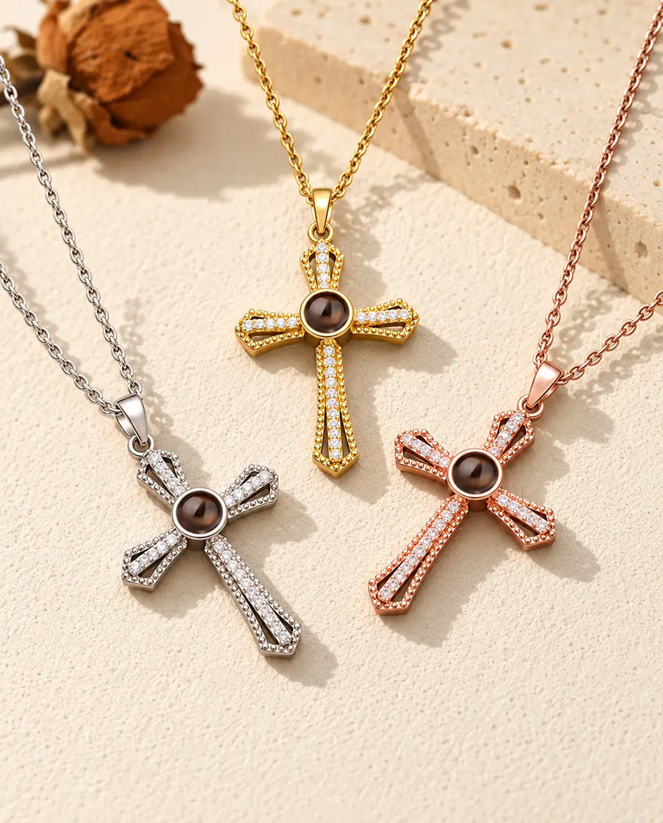 I tre colori della collana con croce a pavé e foto dentro disposti su gesso color crema