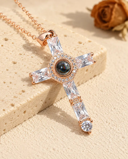 Collana personalizzata color oro rosa con croce di zirconi e foto dentro, accanto al travertino