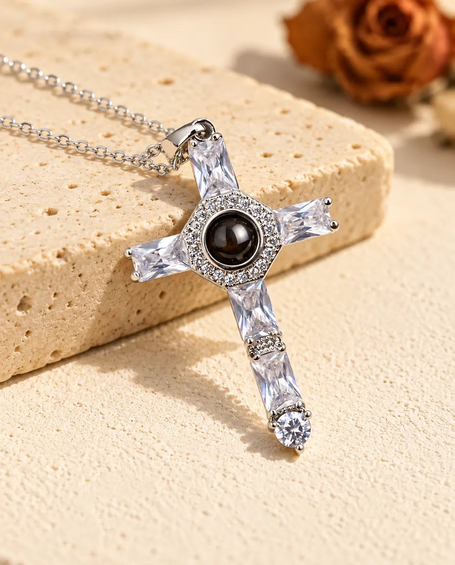 Collana argentata con croce di zirconi e foto dentro appoggiata a un blocco di travertino