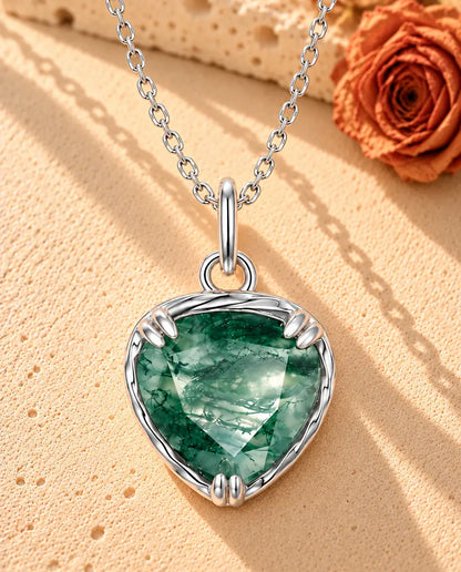 Collana con Ciondolo Cuore in Agata Muschiata e Argento 925 - appoggiata su una superficie chiara ruvida accanto a un blocco di travertino