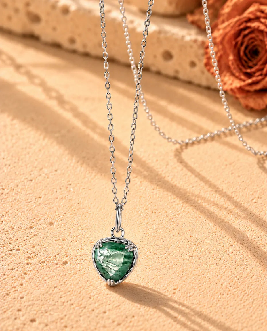 Collana con Ciondolo Cuore in Agata Muschiata e Argento 925 - vista di tre quarti su una superficie chiara ruvida