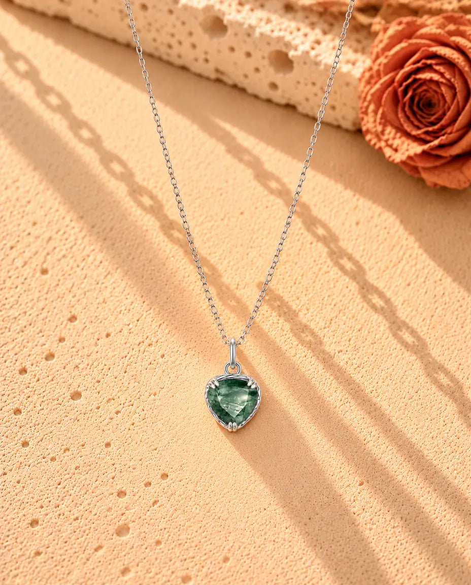 Collana con Ciondolo Cuore in Agata Muschiata e Argento 925 - la collana intera distesa a lunga V su una superficie chiara ruvida