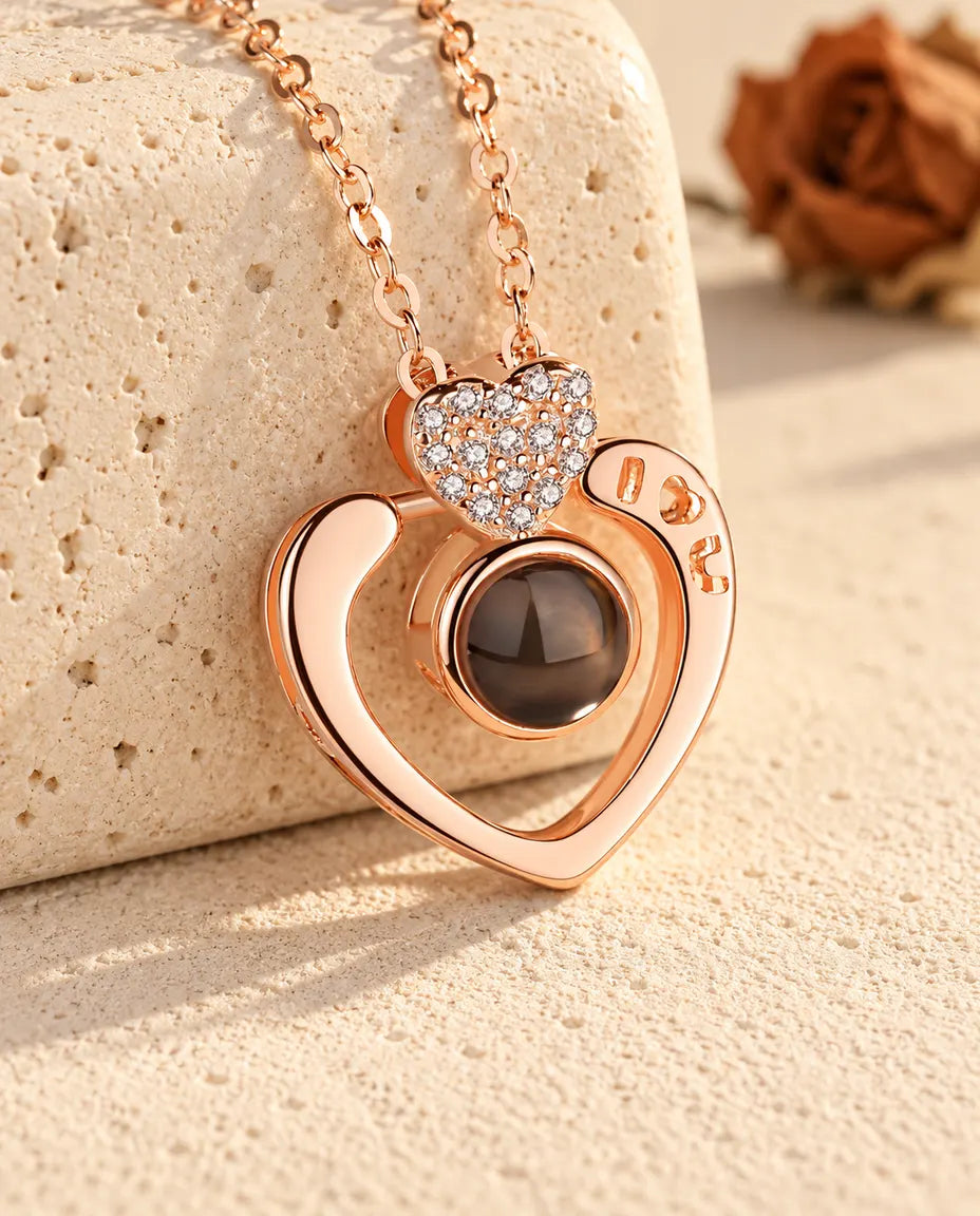 Collana con foto dentro personalizzata color oro rosa, cuore aperto I love U appoggiato a un blocco di travertino