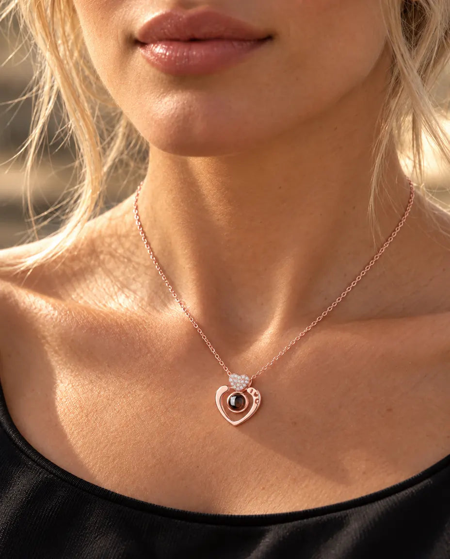 Donna con un top nero che indossa la collana a cuore aperto color oro rosa con foto dentro