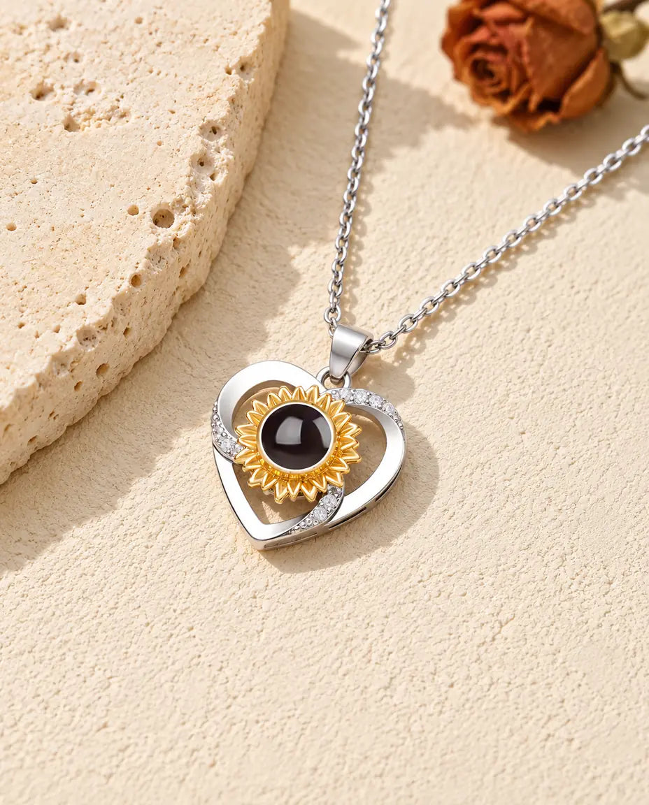 Collana con foto dentro personalizzata con cuore e girasole dorato, appoggiata su una lastra di travertino