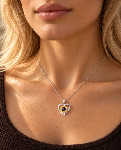 Donna con un top marrone in maglia che indossa la collana con cuore e girasole e foto dentro