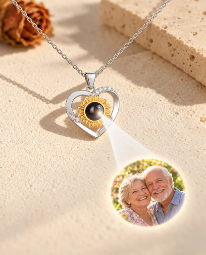 Collana con cuore e girasole che proietta sul gesso crema una foto dei nonni