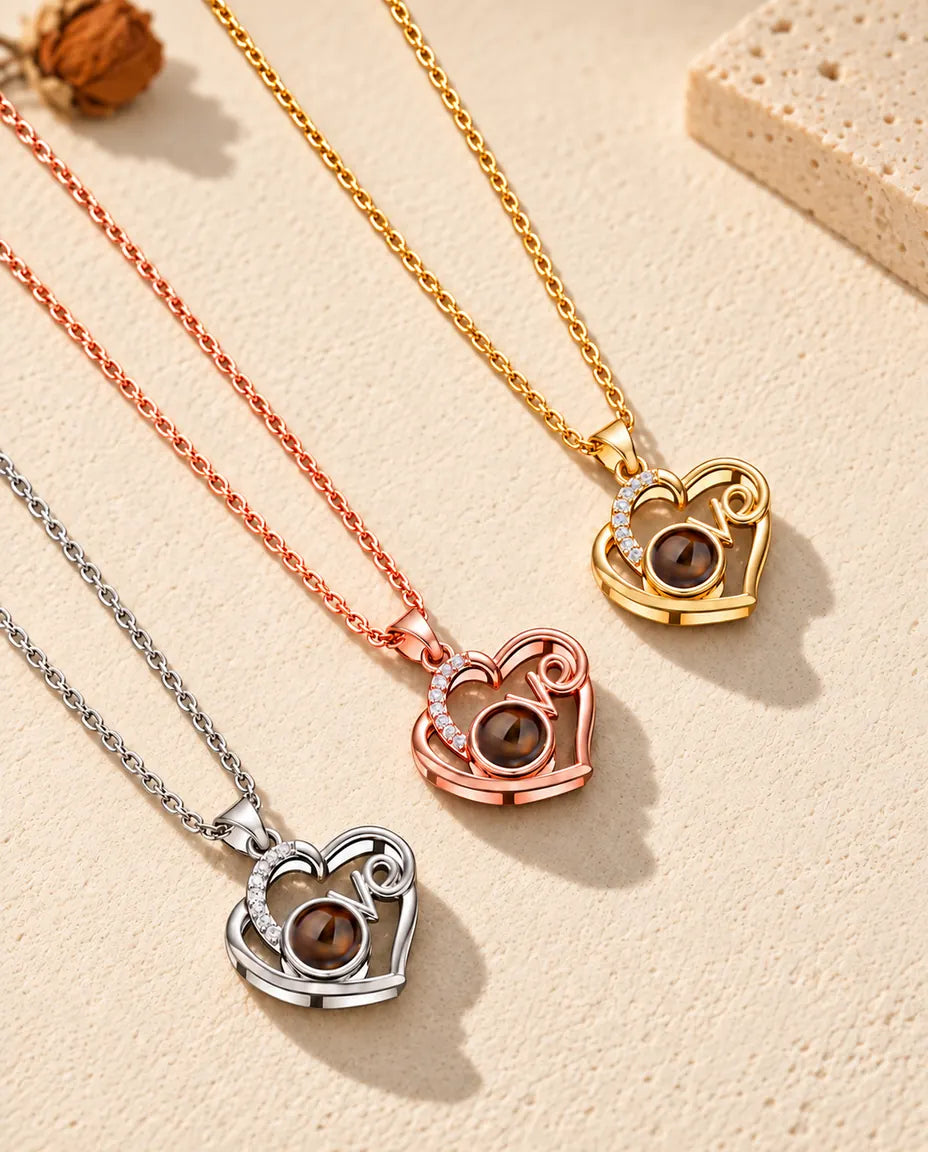 Collane cuore Love argentata, color oro rosa e dorata disposte in diagonale sul gesso