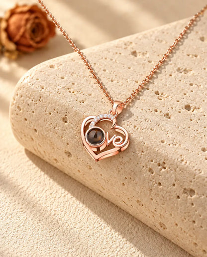 Collana cuore Love color oro rosa con foto dentro sul travertino, alla luce calda del sole