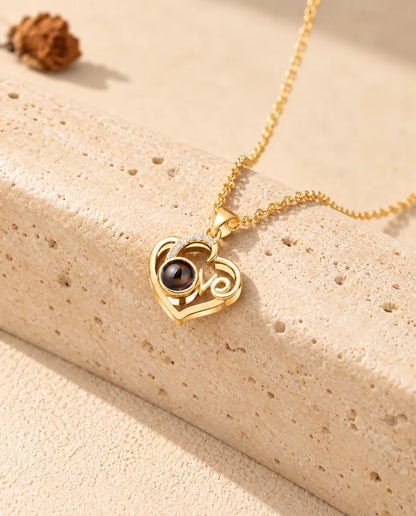 Collana cuore Love dorata con foto dentro appoggiata a un blocco di travertino