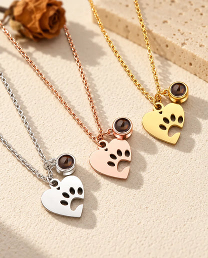 I tre colori della collana con cuore, zampa e foto dell'animale disposti in diagonale su gesso color crema
