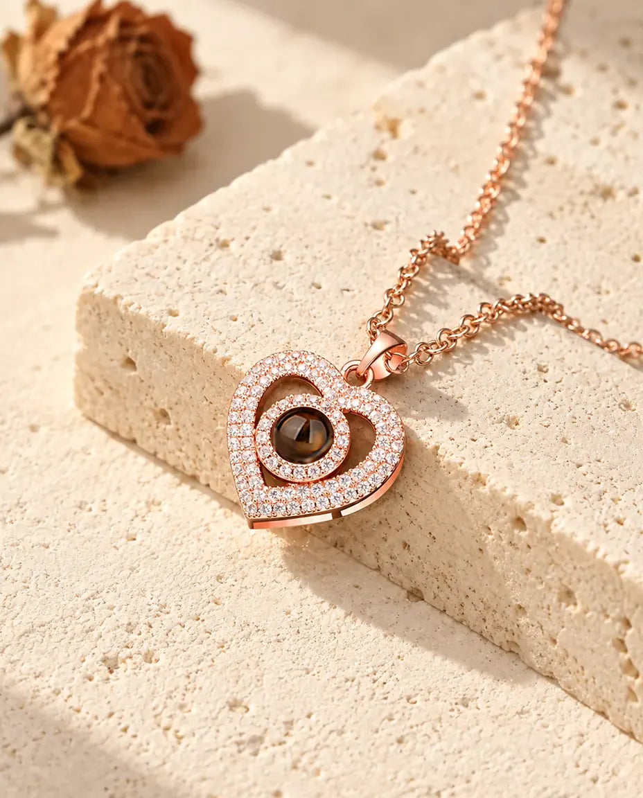 Ciondolo a doppio cuore color oro rosa a pavé appoggiato a un blocco di travertino