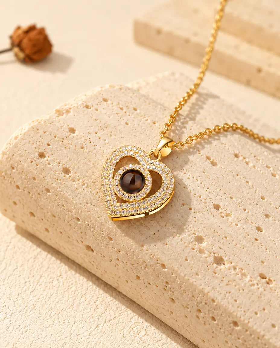 Collana dorata a doppio cuore con la pietra di proiezione al centro, su travertino