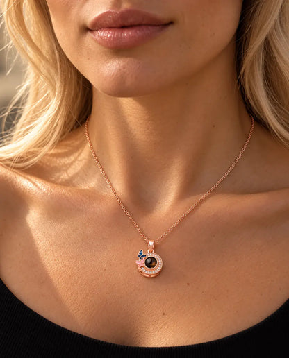 Donna con un top nero in maglia che indossa la collana color oro rosa con farfalle e foto dentro