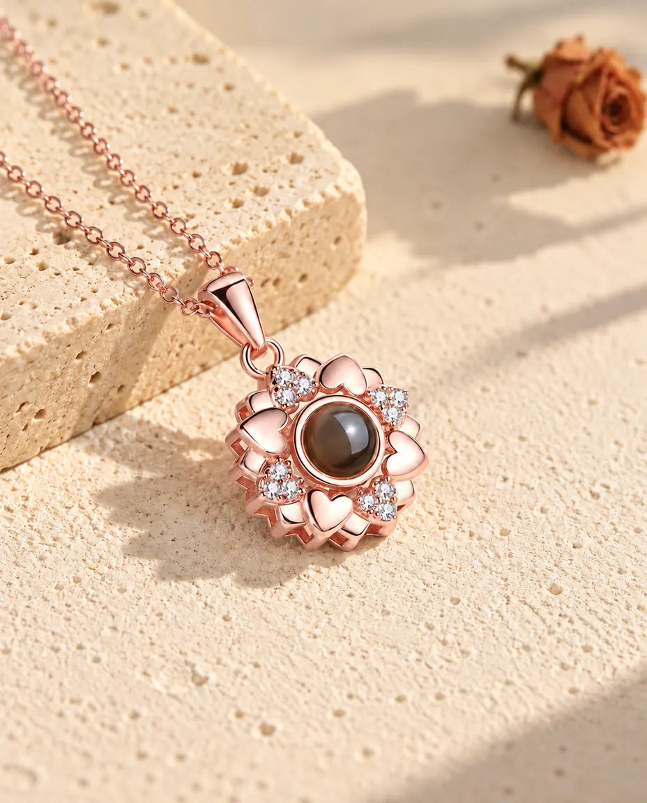 Collana a fiore di cuori color oro rosa appoggiata sul gesso nella luce calda del sole
