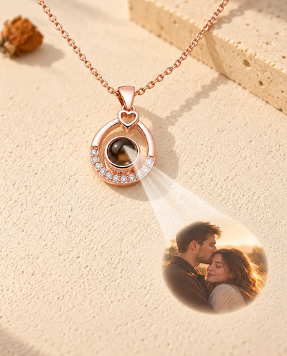 Collana color oro rosa a goccia che proietta la foto di una coppia su intonaco crema