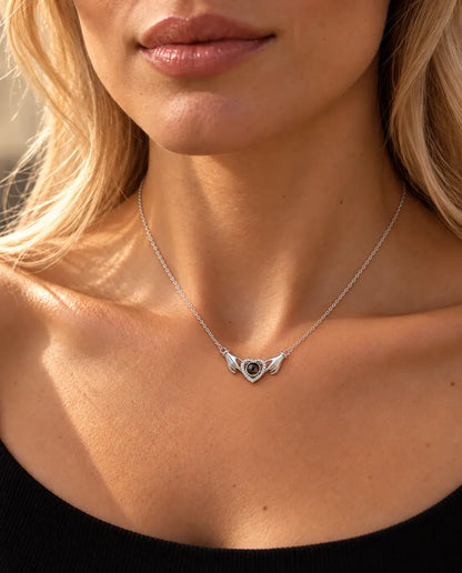 Donna con un top nero in maglia che indossa la collana argentata con due mani che tengono un cuore e foto dentro