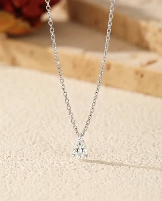 Collana Moissanite a Goccia 1 ct in Argento 925 - ciondolo su una superficie chiara accanto a una lastra di travertino