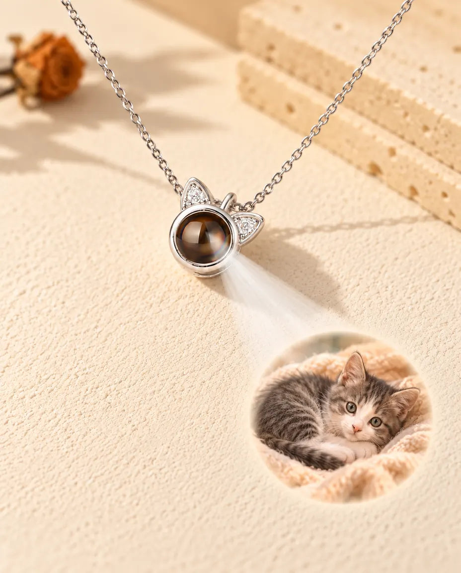 Collana argentata con orecchie di gatto che proietta la foto di un gattino su intonaco crema