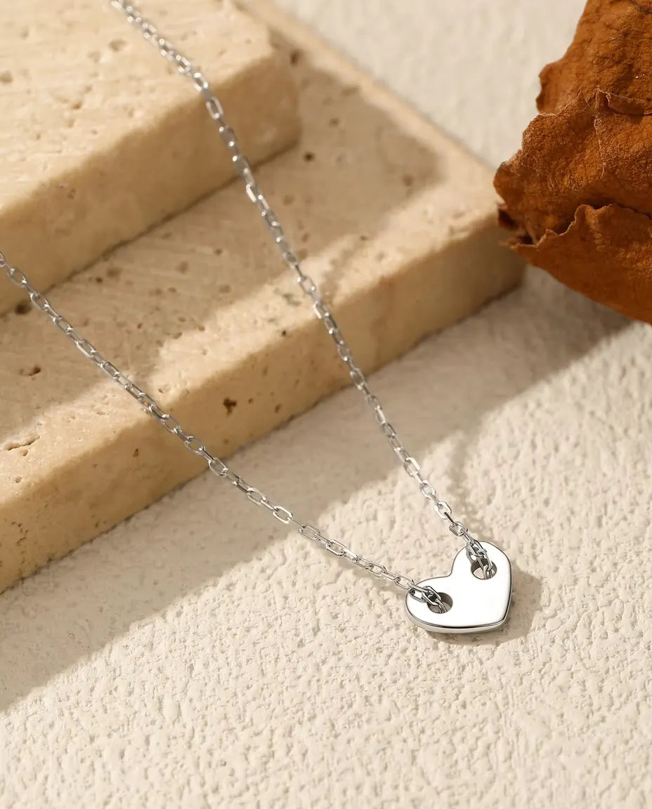 Collana con Cuore in Argento 925 - ciondolo su una superficie chiara accanto a una lastra di travertino