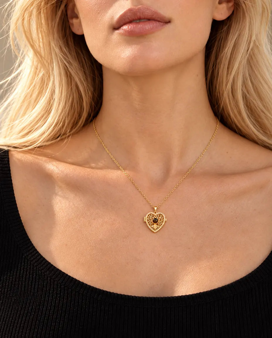 Donna bionda con un top nero che indossa la collana dorata a cuore albero della vita con pietra di proiezione