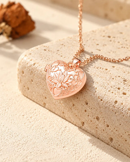 Collana portafoto color oro rosa a cuore con fiore di loto sul travertino, nella calda luce del sole