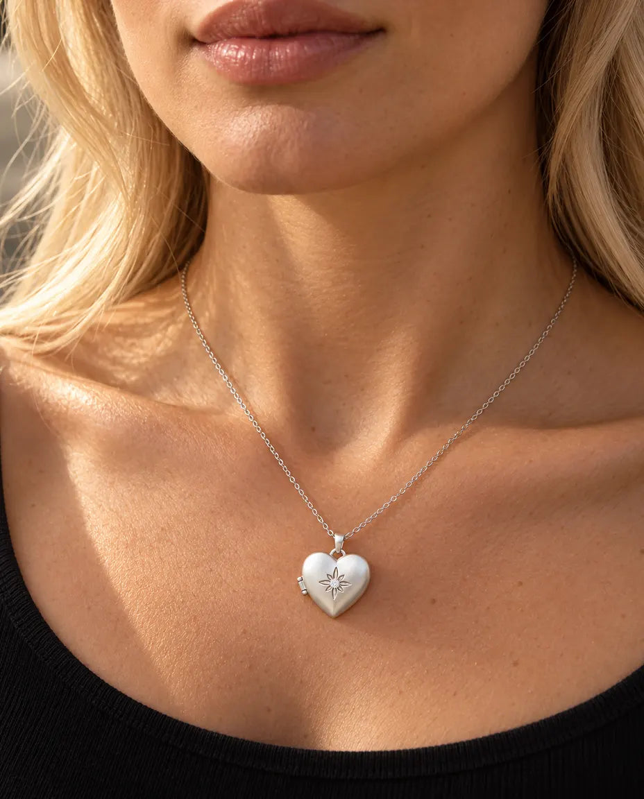 Donna con un top nero in maglia che indossa la collana portafoto a cuore satinato con fiore argentata