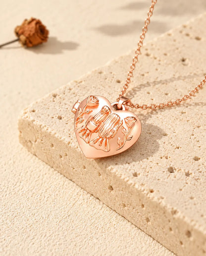 Collana portafoto color oro rosa a cuore Sorelle sul travertino, nella calda luce del sole