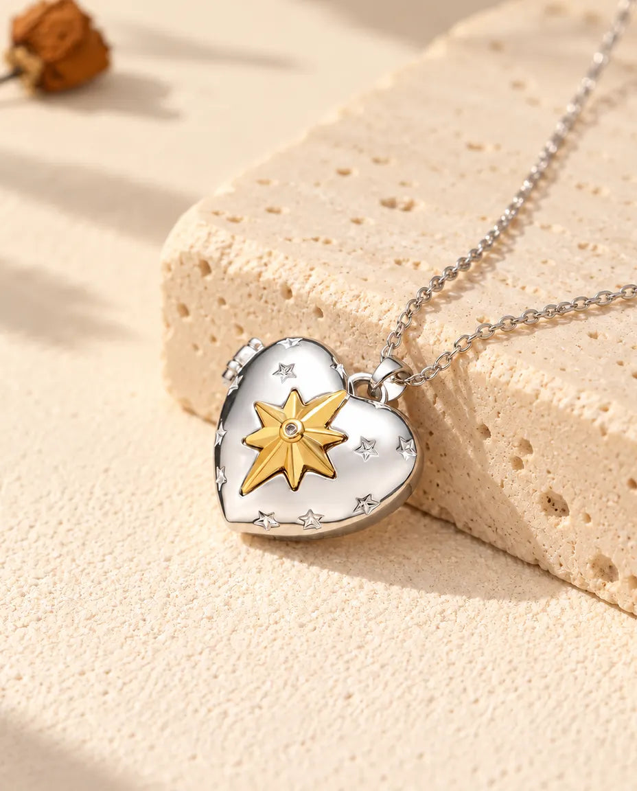 Collana portafoto a cuore con stella polare argentata con stella polare dorata appoggiata a un blocco di travertino