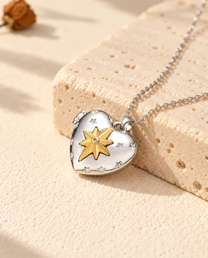 Collana portafoto a cuore con stella polare argentata con stella polare dorata appoggiata a un blocco di travertino