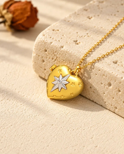 Collana portafoto a cuore con stella polare dorata appoggiata a un blocco di travertino