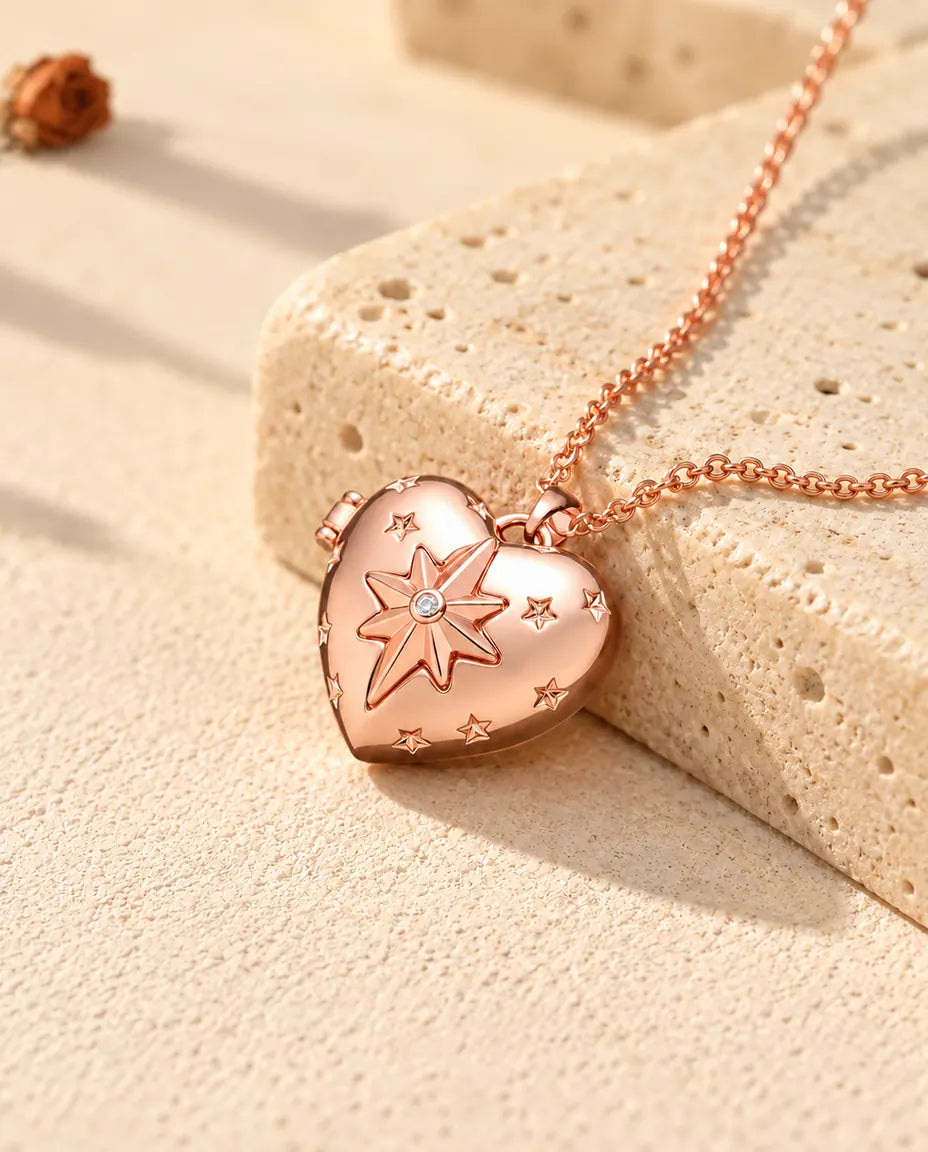 Collana portafoto a cuore con stella polare color oro rosa sul travertino, alla luce calda del sole