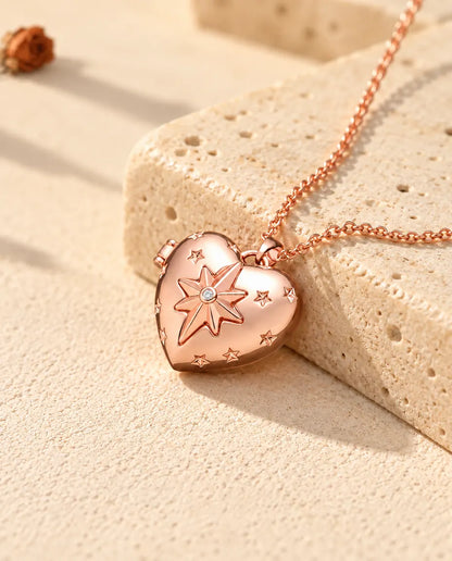 Collana portafoto a cuore con stella polare color oro rosa sul travertino, alla luce calda del sole