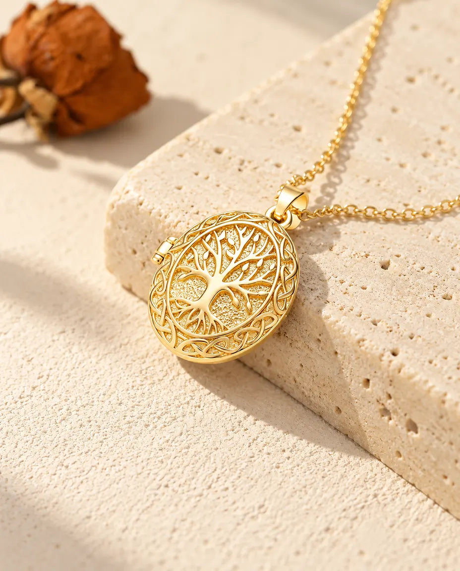Collana portafoto ovale dorata con albero della vita appoggiata sul bordo di un blocco di travertino