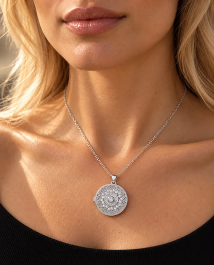 Donna con un top nero in maglia che indossa la collana portafoto argentata tonda con fiore mandala