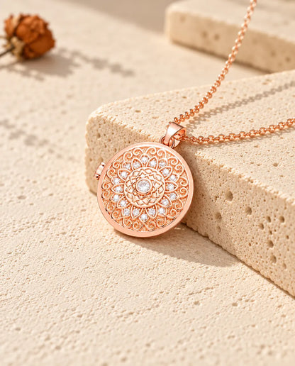 Collana portafoto color oro rosa tonda con fiore mandala sul travertino, nella calda luce del sole