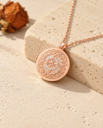 Collana portafoto color oro rosa tonda con nodo celtico a quattro anse sul travertino, nella calda luce del sole
