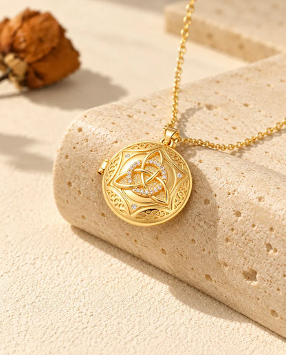 Collana con ciondolo tondo a nodo celtico dorato adagiata su un blocco di travertino