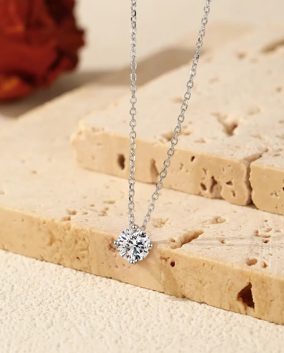 Collana Punto Luce Moissanite 1 ct in Argento 925 - ciondolo appeso al bordo di una lastra di travertino