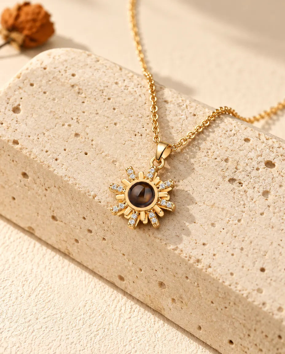 Collana personalizzata dorata a forma di sole con foto dentro, appoggiata su un blocco di travertino