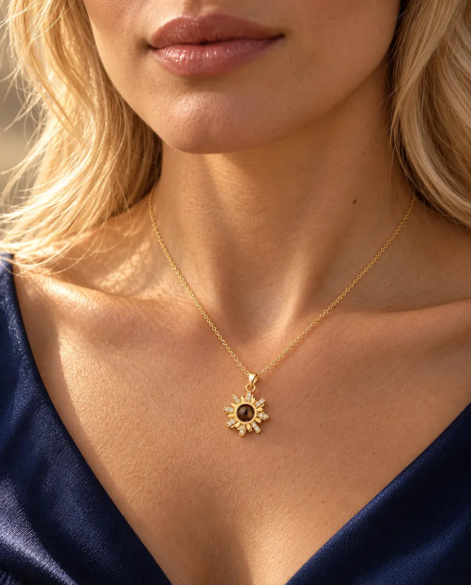 Donna con maglia blu navy che indossa la collana dorata a forma di sole con foto dentro
