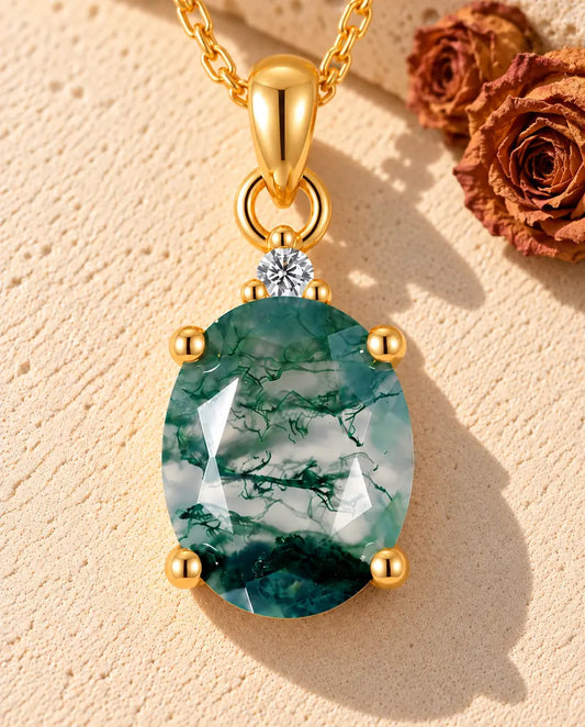 Collana Solitario Agata Muschiata Ovale in Argento 925 Placcato Oro - appoggiata su una superficie chiara ruvida accanto a un blocco di travertino