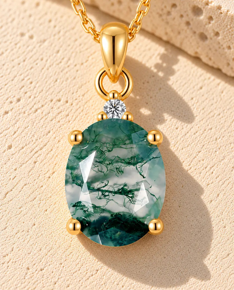 Collana Solitario Agata Muschiata Ovale in Argento 925 Placcato Oro - appoggiata su una superficie chiara ruvida accanto a un blocco di travertino