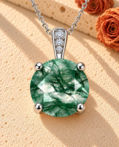 Collana Solitario Agata Muschiata Tonda in Argento 925 - appoggiata su una superficie chiara ruvida accanto a un blocco di travertino