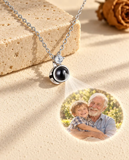 Collana argentata con punto luce che proietta la foto di un nonno con il nipote sull'intonaco